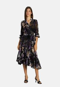 Vestido negro con estampados morados y florales, mangas 3/4, dobladillo con volantes y cintura ceñida con cinturón. Hecho de una tela ligera y fluida.