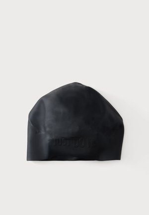 Gorra de natación de silicona negra con texto sutil en relieve de "JUST DO IT." en la parte frontal, mostrada sobre un fondo claro y liso.