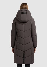 Langer, dunkelgrauer Puffer-Mantel mit einem Zickzackmuster, einer Kapuze und einem Reißverschluss am unteren Ende. Verfügt über ein glänzendes schwarzes Etikett auf der Rückseite.