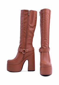 Stivali alti fino al ginocchio in finta pelle marrone, con punta rotonda, chiusura con zip e una larga fascia con un accento in metallo a forma di anello.