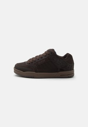 Donkerbruine lage sneaker met dikke zool, vetersluiting aan de voorkant en "GLOBE"-opdruk aan de zijkant en hak.