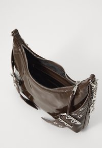 Borsa a tracolla in pelle verniciata marrone con chiusura con zip, accessori in argento e una trama laterale texturizzata con ritagli e borchiette. Comparti interni visibili.
