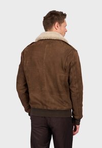 Giacca bomber in pelle marrone con colletto in shearling crema, orlo a coste e polsini elasticizzati; presenta una texture liscia e un design aderente.