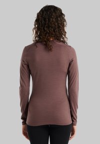 Pitkähihaiseen, istuvaan puseroon mauve-kankaasta, sileä tekstuuri, pyöreä kaula-aukko ja raglan-hihat. Korostaa minimalista muotoilua, ei näkyviä kuvioita.