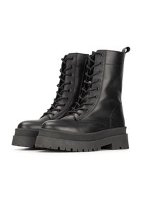 Bottes en cuir noir à lacets avec un tige haute, semelle en caoutchouc épaisse et finition texturée. Caractéristiques : bout rond et détails de couture renforcés.