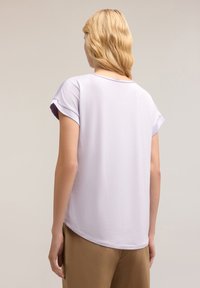 Top corto de manga corta en color lila con un corte relajado, escote redondo y textura suave. Las mangas enrolladas y el dobladillo curvado añaden detalles de diseño sutiles.