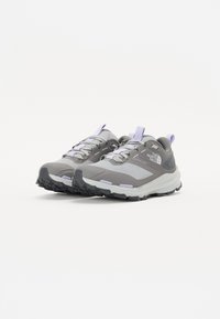 Chaussures de randonnée grises avec des accents violets, fabriquées en matériaux en maille et synthétiques, dotées d'une semelle en caoutchouc texturé et d'un design de soutien.
