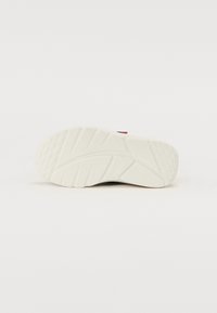 Shoe outsole in white rubber, featuring a textured surface with a geometric tread pattern for grip and durability, and a slight heel elevation.