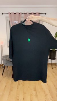 Camiseta de manga larga negra, con un pequeño logo de diamante verde en el pecho. Fabricada con una tela suave y con un corte holgado.