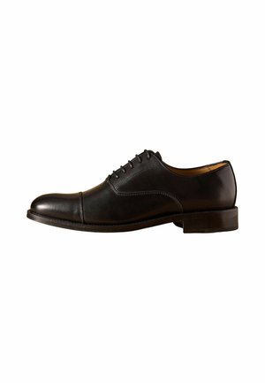 Schwarzer Herren Oxford Lederschuh mit geschlossenem Schnürsystem, Kappzehen und niedrigem gestapeltem Absatz, seitlich auf weißem Hintergrund dargestellt.