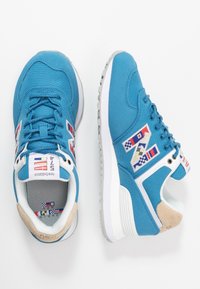 Baskets en toile bleue avec des accents blancs, un logo brodé et un panneau de talon tan. Semelle en caoutchouc épaisse avec un motifs texturé.