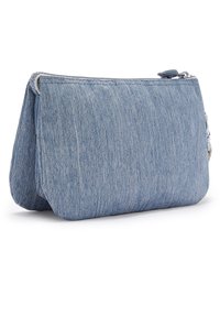 Bolsita de denim en azul claro. Presenta una superficie texturizada, cierre de cremallera y detalles de costura sutiles. Forma rectangular con bordes redondeados.