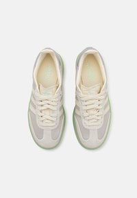 Light gray and cream sneakers with textured suede, three stripes design, green translucent sole, and laces. Interior features Adidas branding.