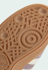 Smeđi gumeni potplat sa geometrijskim uzorkom i kružnim detaljima, sa uzdignutim linijama i teksturama za bolji grip i izdržljivost.
