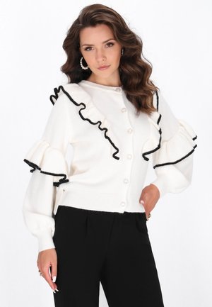 Weißer Pullover mit schwarzen Rüschendetails an Schultern und Ärmeln. Mit runden Knöpfen und gerippten Bündchen, aus weichem, strukturiertem Stoff.