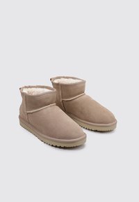 Botines cortos de ante beige con forro suave de piel. Punta redonda, diseño de perfil bajo y suela de goma con patrón antideslizante. Ligeros e informales.