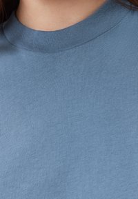 T-shirt in cotone blu con scollatura rotonda e una texture liscia e morbida. Il tessuto è leggero e presenta un leggero elastico.