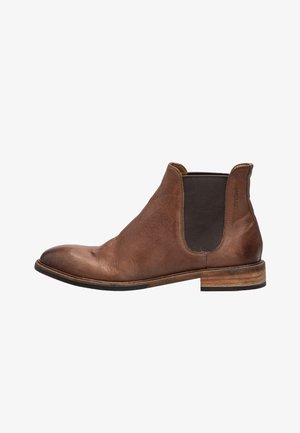 Bottines Chelsea en cuir brun avec des panneaux élastiques sur les côtés et un talon empilé. Présente une texture lisse et un design à bout rond.