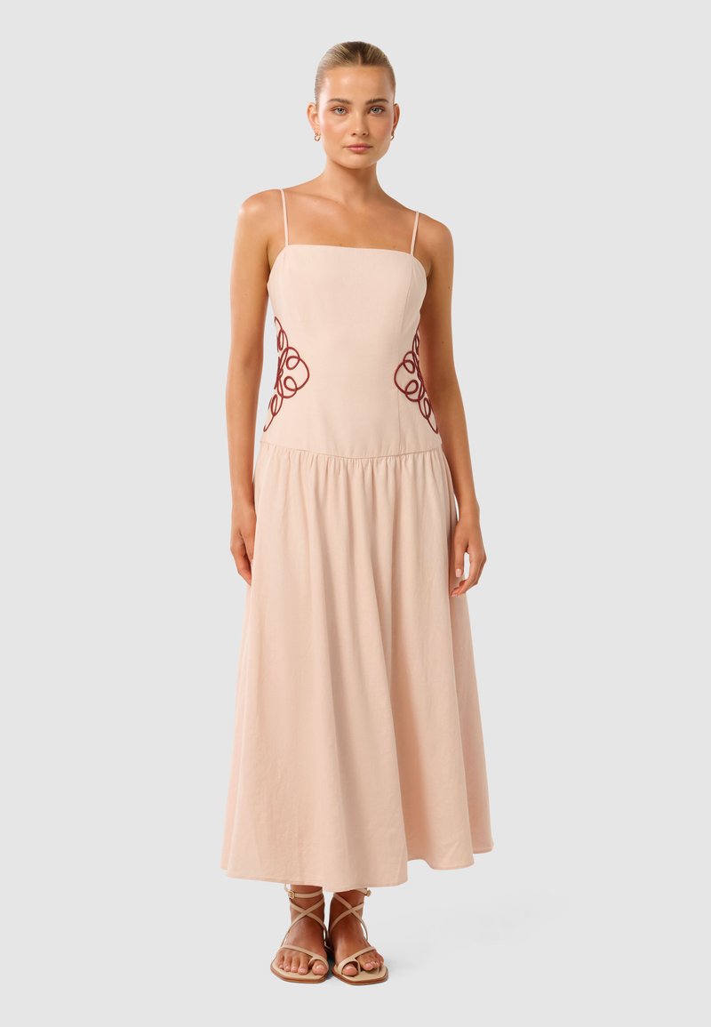 Lichtroze mouwloze jurk met een aansluitend lijfje en een luchtige rok, versierd met cirkelvormige bordeauxrode borduursels aan de zijkanten. Soepele stoftextuur.