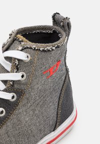 Džínová vysoká obuv s kombinací šedé a černé tkaniny, bílými tkaničkami, červeným logem a roztrhanými okraji na límci a švech.