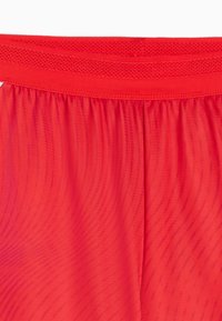 Pantalones cortos deportivos rojos con acabado texturizado, cintura elástica con detalles de malla y tejido ligero y transpirable.