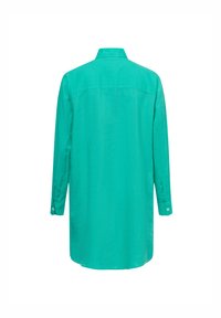 Maglietta a maniche lunghe di un vivace color turchese, realizzata in un tessuto liscio. Presenta un retro con yoke e polsini con bottone, evidenziando un design minimalista.
