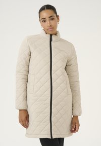 Beige gesteppter Mantel mit hohem Kragen, langen Ärmeln und einem Frontreißverschluss. Verfügt über diagonale Nähte und zwei Fronttaschen.
