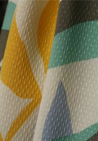 Texturerad tyg med färgglada geometriska mönster i gult, teal, grått och ljusblått, med en prickig yta och vävd design.