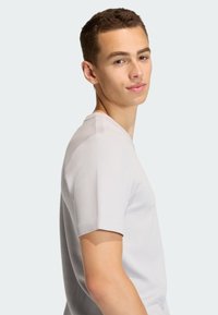 Svetlosivé tričko s krátkym rukávom s textúrovaným vzorom a výstrihom do V, s priliehavým strihom a hladkou látkou.