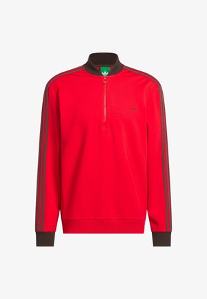 Sweatshirt vermelho com fecho e gola e punhos canelados castanhos; apresenta riscas cinzentas nas mangas e um pequeno logótipo no peito.