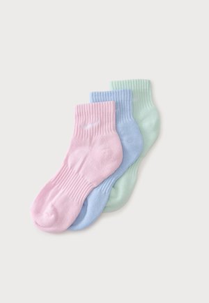 Trois paires de chaussettes courtes côtelées aux couleurs pastel rose, bleu et vert empilées sur un fond gris clair.
