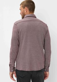 Langarmshirt in een bordeauxrode tint, gemaakt van gestructureerde stof met een subtiel patroon. Heeft een kraag en knoopmanschetten.
