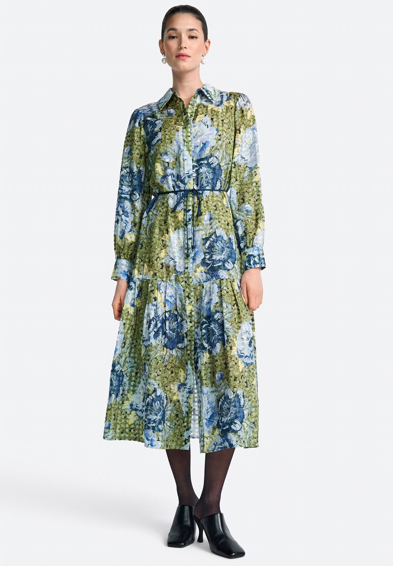 Virágmintás midi ruha zöld és kék színvilággal, gallérral, hosszú ujjakkal, megkötős derékpánttal és réteges szoknyával. Texturált anyag.