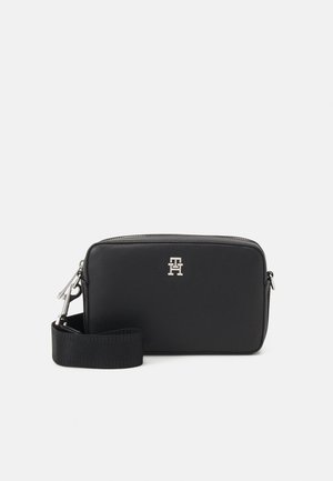 Borsa a tracolla in pelle nera con texture liscia, forma rettangolare, hardware in argento e tracolla rimovibile. Presenta un logo sulla parte frontale.