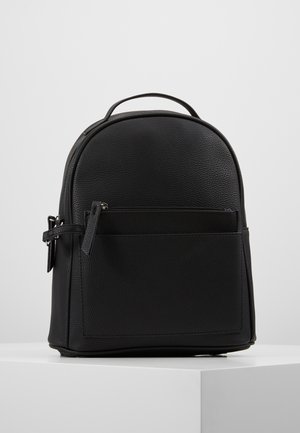 Kleiner schwarzer Rucksack aus strukturiertem Leder mit einem oberen Griff, einer vorderen Reißverschlusstasche und verstellbaren seitlichen Riemen auf einer weißen Oberfläche.