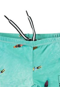 Turkosa badshorts med en slät textur, prydda med färgglada surfbrädemönster. Svart och vit dragsko i midjan.
