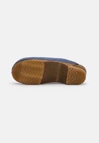 Blauwe leren schoen met een gestructureerde bovenkant, voorzien van een bruine rubberen zool met een zigzagpatroon en een houten accent op de hak.