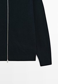 Schwarzer, gestrickter Reißverschluss-Pullover mit Silberreißverschluss, gerippten Bündchen und Saum, glatter Textur und taillierter Silhouette.