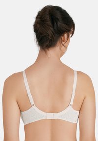 Draadloze beha in beige met bloemenpatroon, verstelbare bandjes en haak-en-oogsluiting. Gladde textuur, aansluitend ontwerp, zachte stof.