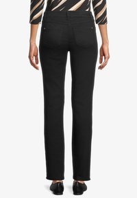 Svarta rakbenade jeans med bakfickor, slät textur och midjeband. Bärs med en mönstrad topp och svarta skor.