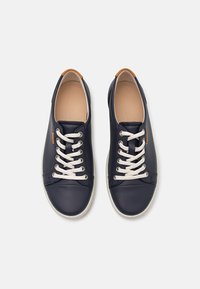 Navy blue leather sneakers with white laces and a light-colored sole. Features a tan leather accent at the heel and smooth texture throughout.