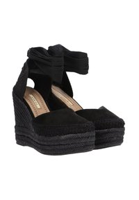 Wedges de espadrilles negras con parte superior de lona texturizada, una cinta ancha cruzando el tobillo y una suela de cuerda trenzada. Diseño simple de punta cuadrada.