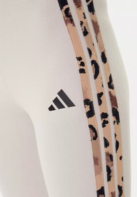 Leggings in cotone grigio chiaro con una vestibilità a vita alta, caratterizzati da strisce laterali in stampa leopardata nera e marrone e un logo Adidas nero.
