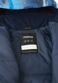 Interior de una chaqueta aislante azul marino con una textura suave, que presenta una etiqueta con "reima", tamaño 104, y detalles sobre sostenibilidad.
