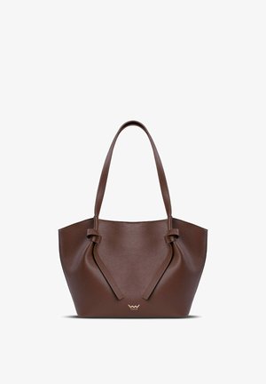 Brown leather tote bag with a pronounced shape, featuring tied accents on the sides and gold logo at the base. Smooth texture.