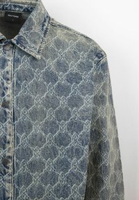 Denimjack voor een lichte blauwe en witte geometrische patroon, klassieke kraag en zwarte knoopsluiting aan de voorkant. Textuurstof.