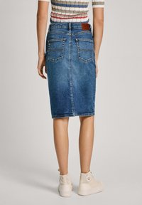 Denim blyantskørt i mellemblå, med to baglommer, en glat tekstur og en tætsiddende silhuet. Inkluderer et lædermærke ved taljen.