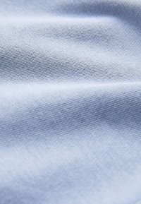 Lyseblåt stof med en diskret tekstur og ensartet vævning, med mindre rynker, der skaber et blødt udseende. Velegnet til tøj eller polstring.