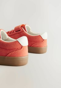 Różowe zamszowe buty z wyściółką w kolorze białym i brązową gumową podeszwą. Posiadają okrągłe sznurówki oraz rzep do łatwego zapinania.