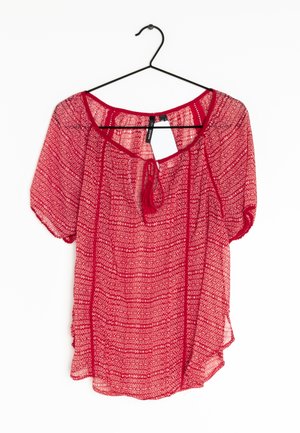Blusa rossa trasparente con maniche corte e scollatura rotonda. Presenta una texture a motivo con dettaglio annodato nella parte anteriore e appende a un gancio.